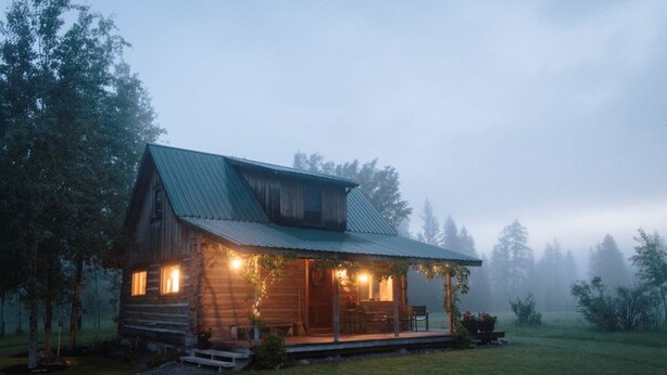 A rustic cabin with a porch, wooden exterior, and a small deck.