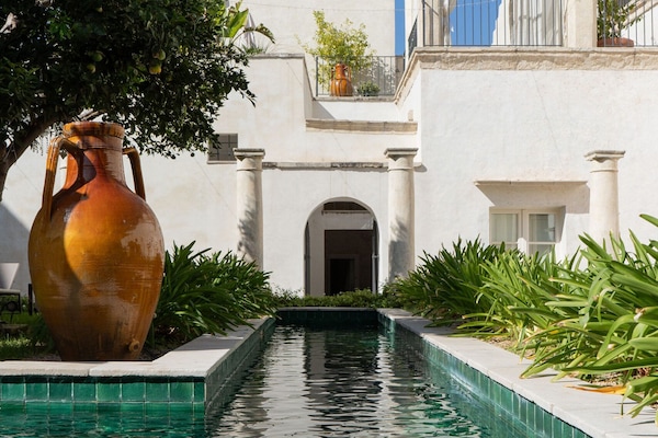 Una piscina al aire libre, sombrillas, sillones reclinables de piscina