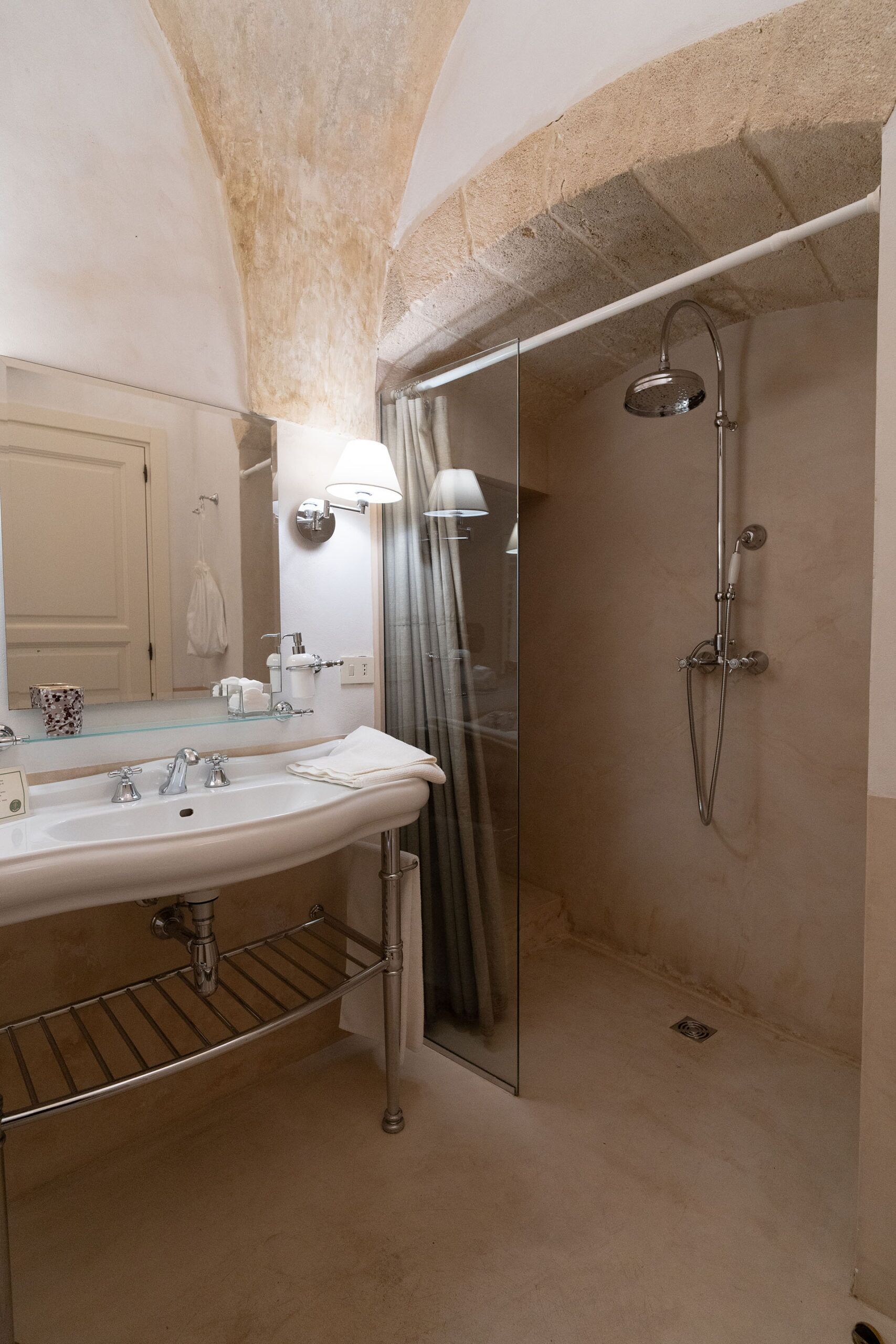 A bathroom with a large mirror, a sink, a shower, and a towel rack.