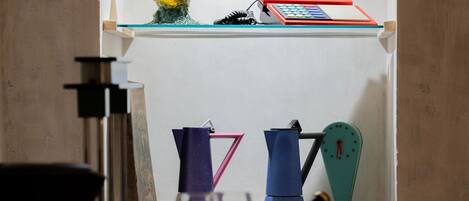 A small, well-lit room with a white shelf containing various items including a yellow object, a red box, and a blue item.