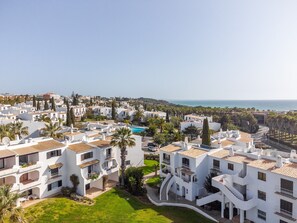 A coastal residential area with white buildings, a swimming pool, and a clear view of the sea. - Apt. 89-A São Rafael by HelloVacations (Albufeira)