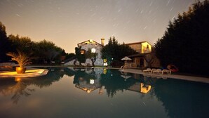A nighttime view of a swimming pool with a stone building in the background, surrounded by trees and a clear sky with star trails. - Villa Lav (Bale)
