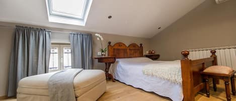 Une chambre avec un puits de lumière, un lit, un canapé et une tête de lit en bois.