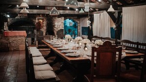 A long dining table set for a meal in a rustic room with exposed wooden beams and stone walls. - Villa Lav (Bale)