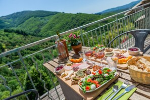 Een tafel gedekt met diverse gerechten en drankjes, met uitzicht op een bergachtig landschap.