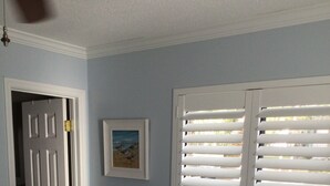A bedroom with a bed, a door, a window with blinds, and a framed picture on the wall. - Very Desirable 1st Floor Villa at Fiddler's Cove Beach & Racquet Club (Hilton Head Island)