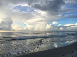 Een strand met golven en een bewolkte lucht.
