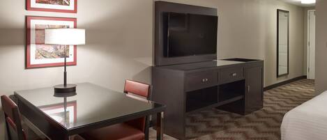 Une chambre d’hôtel comprenant un lit, une télévision, un bureau avec une chaise et un sol recouvert de moquette.