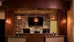 A reception area with a stone wall, a flat-screen TV, and two reception desks. - Oxford Casino Hotel (Oxford)