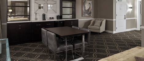 A modern kitchen with dark cabinets, a central island, and a dining area with a table and chairs.