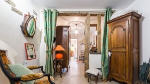 Un couloir avec un meuble en bois, une chaise, une lampe et une table.