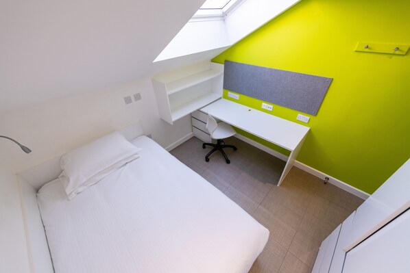 A bedroom with a bed, a desk, and a bright green accent wall.