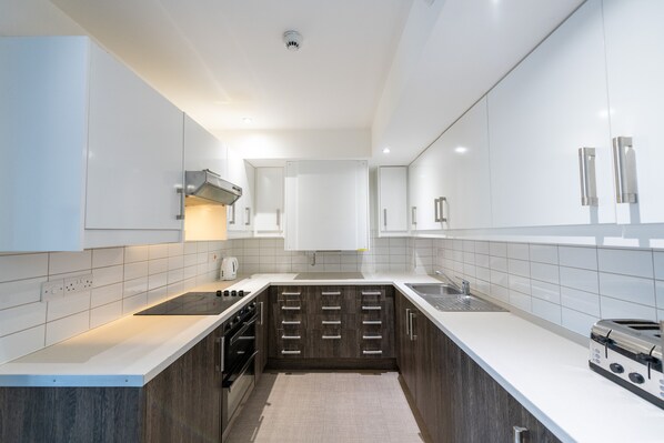 A modern kitchen with white cabinetry, a built-in oven, and a toaster. - University of Bath City Accommodation (Bath)