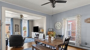 A dining area with a wooden table, chairs, a bench, and a ceiling fan.