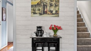 A kitchen with a coffee maker, mugs, and a vase of flowers on the counter.
