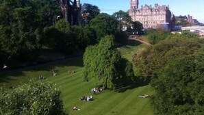 A large, historic building with a prominent clock tower and a spire, surrounded by lush green parkland. - Drumorne Guest House (Edinburgh)