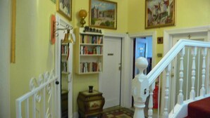 A hallway with a white staircase, a bookshelf, and a door leading to another room. - Drumorne Guest House (Edinburgh)