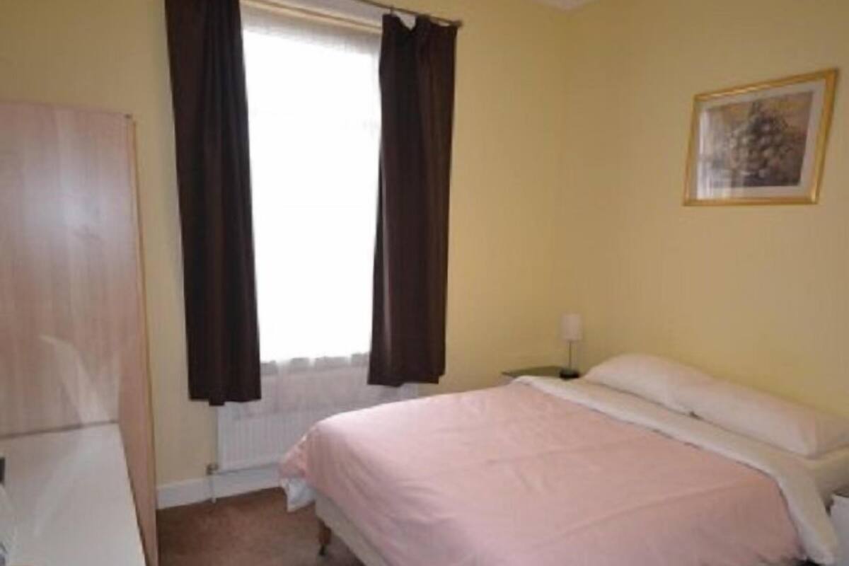 A bedroom with a bed, a nightstand, a lamp, and a radiator.