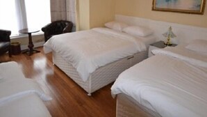 A hotel room with two beds, a chair, a small table, and a painting on the wall. - Drumorne Guest House (Edinburgh)