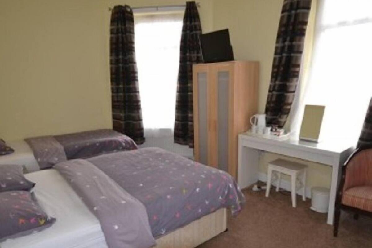 A bedroom with a bed, a desk, a chair, and a wardrobe.