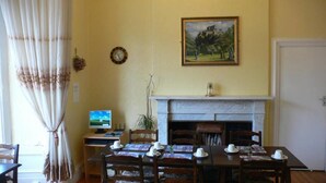 A dining room with a fireplace, a painting on the wall, and a computer on a desk. - Drumorne Guest House (Edinburgh)