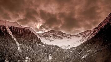 A mountainous landscape with snow-covered peaks and dense forests.