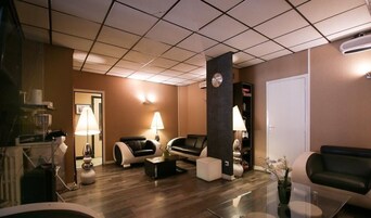 A modern living room with leather sofas, a coffee table, and a glass table. There is a clock on the wall and a door in the background.