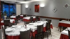 Un restaurante con varias mesas dispuestas para comer, con una decoración en tonos rojo y blanco.