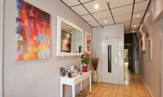 A hallway with a white console table, a large abstract painting, and a mirror.