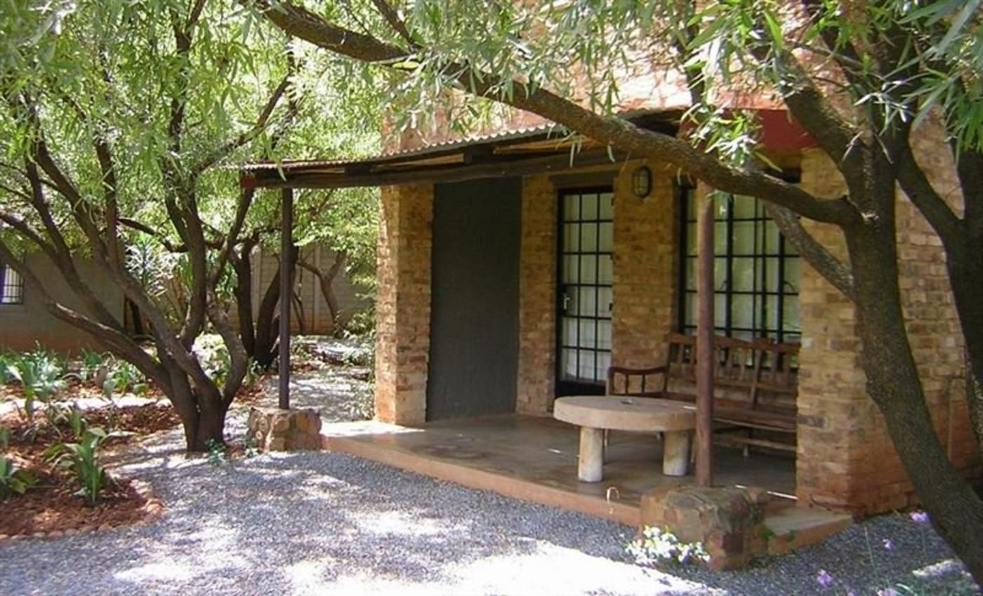 Un edificio de piedra rústico con un porche cubierto, un banco y una puerta.