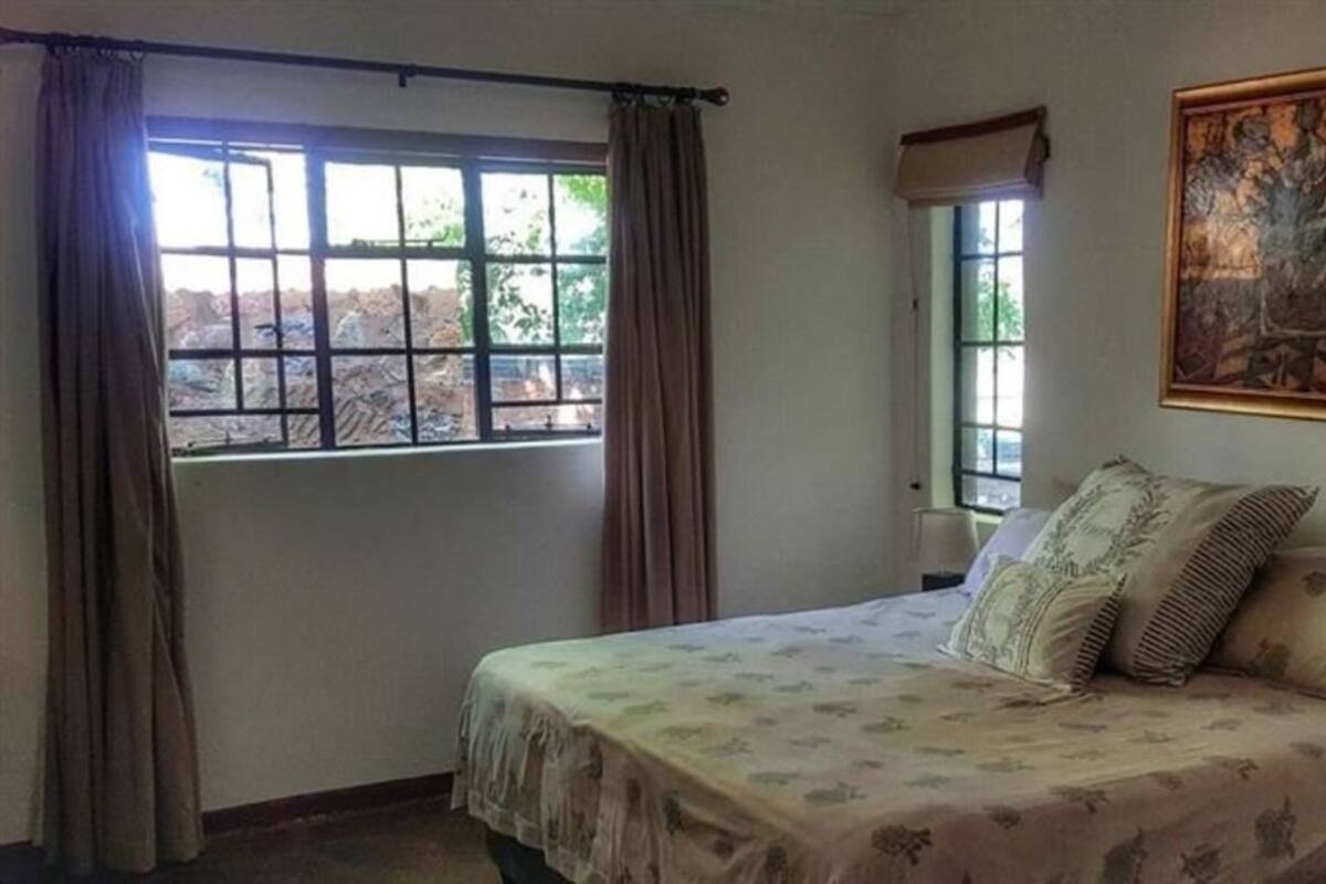 Un dormitorio con una cama, una ventana con cortinas y un cuadro en la pared.