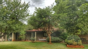 A house with a red roof, surrounded by a well-maintained lawn and several trees. - La Bastide Guesthouse (Hartbeespoort)