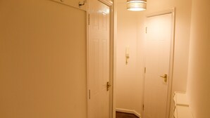 Ein schmaler Flur mit weißen Türen und Holzboden.