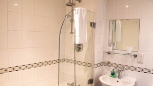 A bathroom with a glass-enclosed shower, a white sink, and a mirror above the sink.