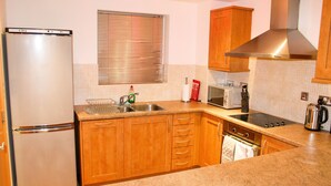 A kitchen with wooden cabinets, a stainless steel refrigerator, a microwave, and a stove.