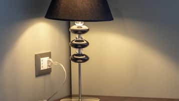 A desk with a lamp, a power outlet, and a book.
