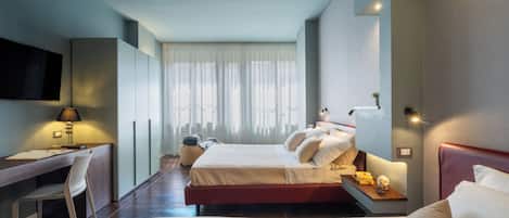 Habitación de hotel con dos camas, un escritorio, una silla, un televisor y una ventana con cortinas.