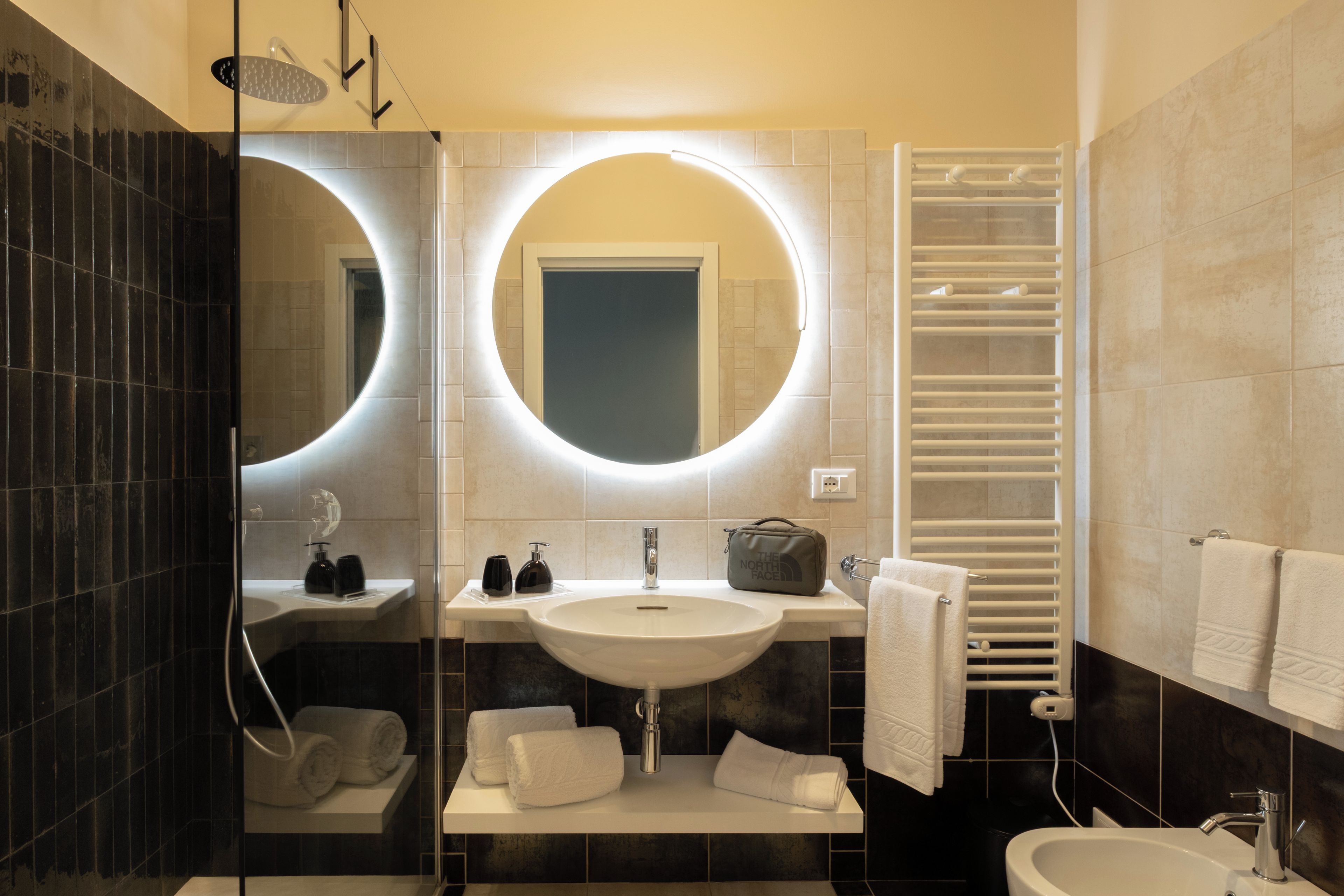 Un bany modern amb un mirall gran, un lavabo, un vàter i una barra de tovalloles.