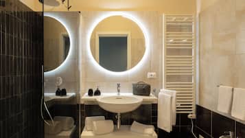 Un bany modern amb un mirall gran, un lavabo, un vàter i una barra de tovalloles.