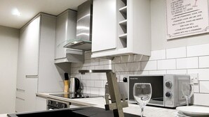 A modern kitchen with a black induction cooktop, a glass coffee pot, and a wine glass on the counter. - Ropewalks Retreat (Liverpool)