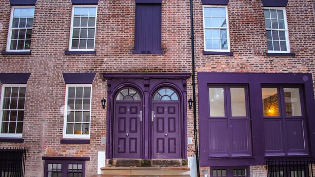 A brick building with two prominent purple doors and a set of steps leading to the entrance. - Ropewalks Retreat (Liverpool)