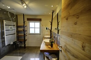 A modern bathroom with a wooden vanity, a large mirror, and a window.