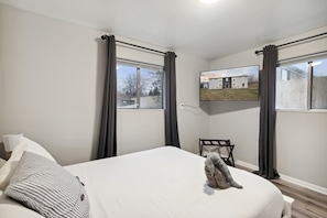 A bedroom with a bed, curtains, a chair, and a television on the wall.