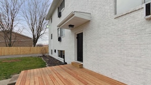 A white brick building with a wooden deck and a black door. - Lansing Layover #4 | New York State of Mind (Lansing)