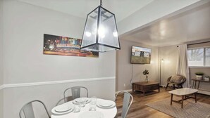 A dining area with a round table, chairs, and a hanging light fixture. - Lansing Layover #4 | New York State of Mind (Lansing)