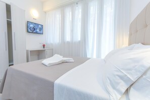 A hotel room with a bed, a TV on the wall, a desk, and a wardrobe. - Hotel Tourist Meuble (Rimini)