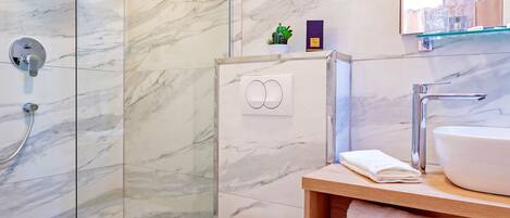 Ein modernes Badezimmer mit einer Duschkabine, einer Toilette und einem Waschtisch mit Waschbecken und Handtuch.