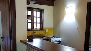 Una cucina con isola in mattoni, sedie in legno, una finestra e un fornello.