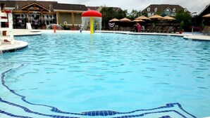 A swimming pool with a tiled edge, a water slide, and lounge chairs.