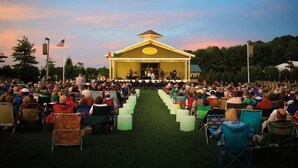 A large outdoor gathering with rows of chairs facing a stage.